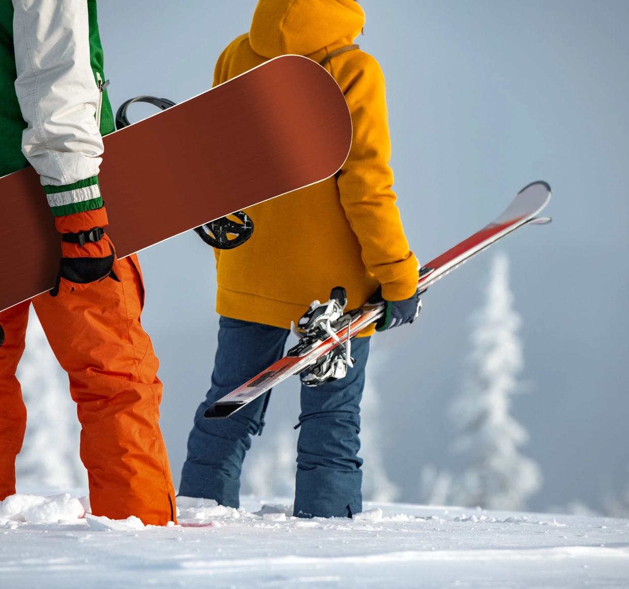 Snowboarder and skier in snowy landscape.