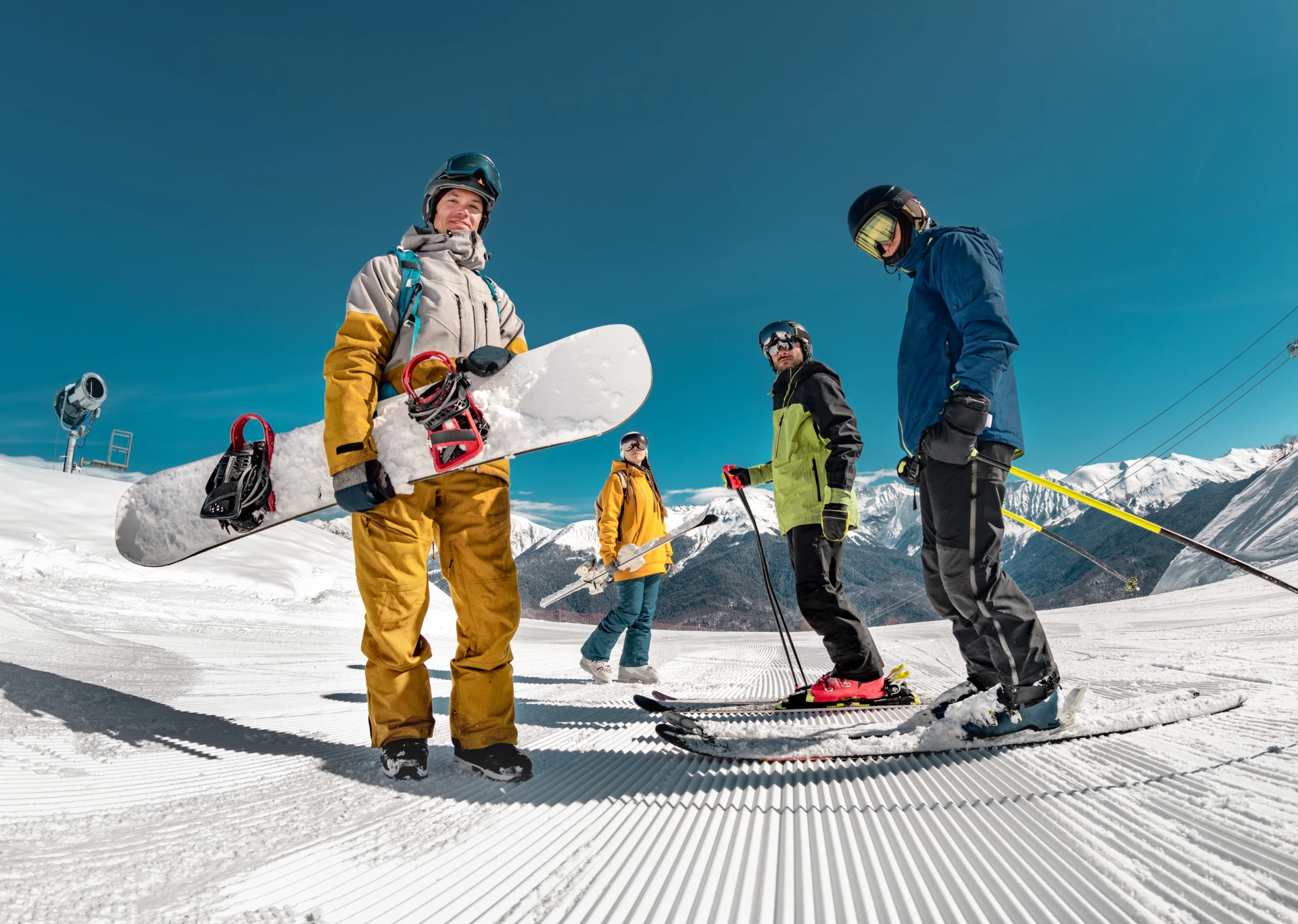 Snowboarders and skiers pose on mountain slope.