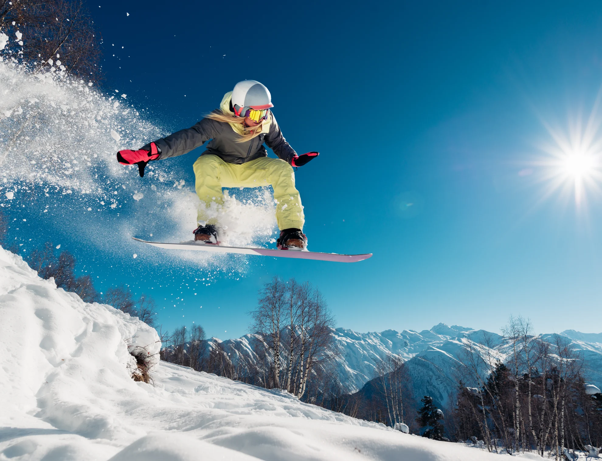 Snowboarder jumping, snowy mountain background.