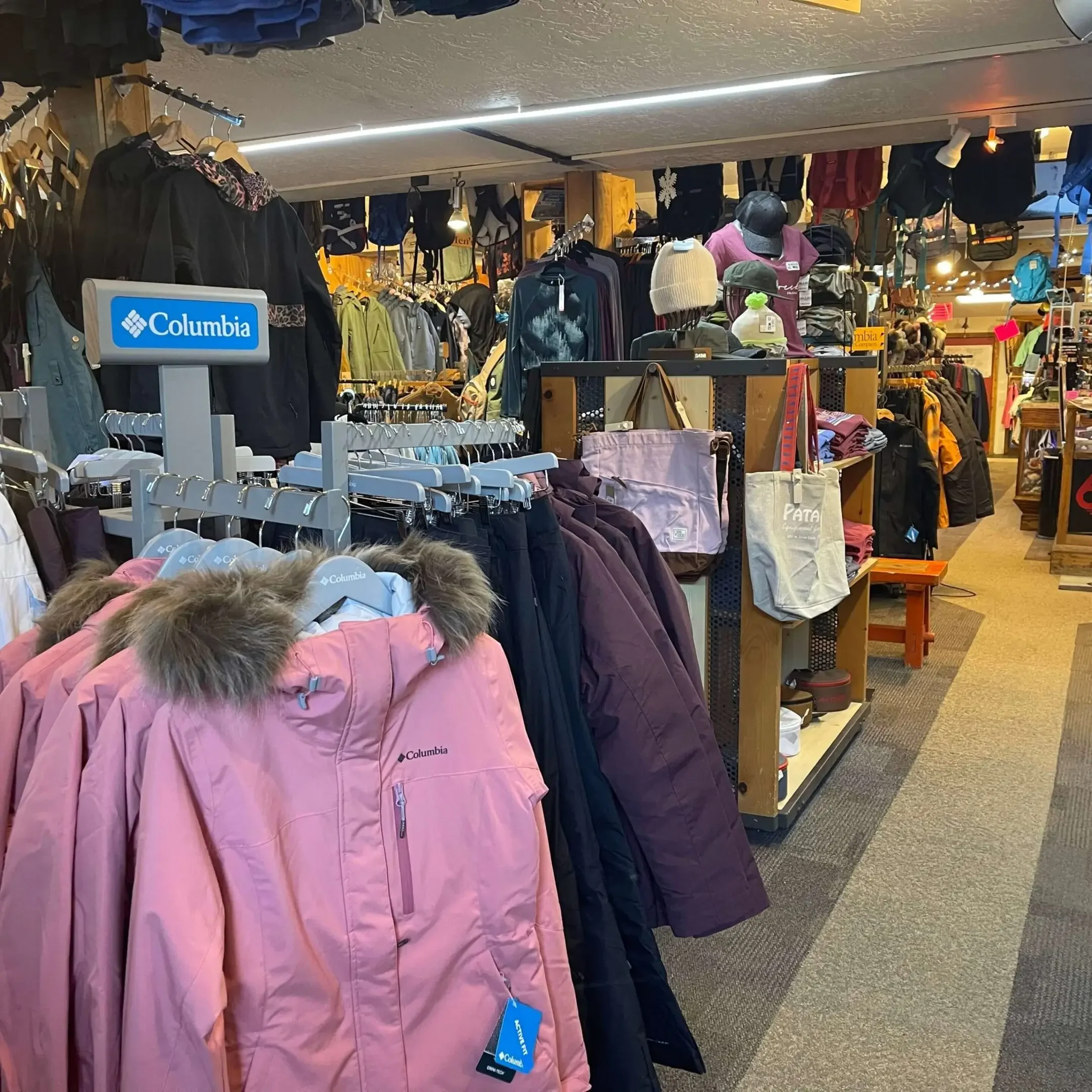 Winter jackets on display in a busy indoor clothing store.
